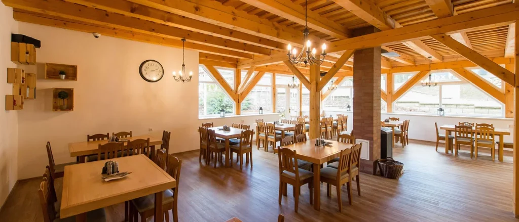 interier restaurace osvětlený, dřevěný nábytek, světlé dřevo, prosklená místnost